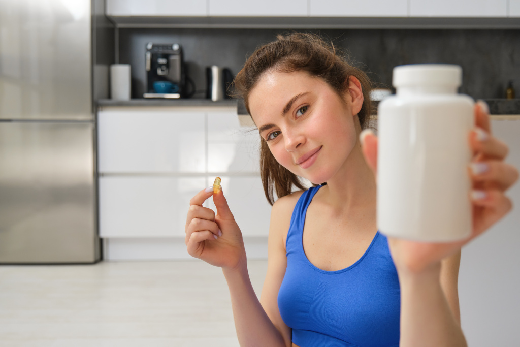 close-up-portrait-of-young-woman-fitness-instructor-showing-bottle-of-vitamins-taking-buds.jpg