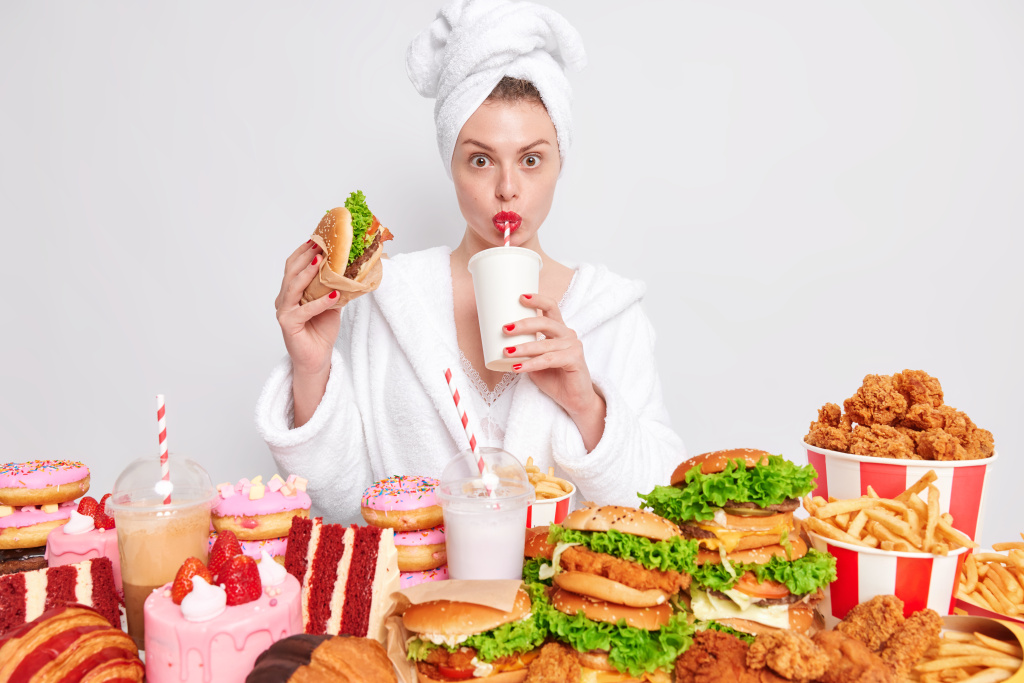 unhealthy-nuttrition-concept-housewife-with-red-manicure-and-lips-in-domestic-bathrobe-towel-on-head-drinks-soda-eats-junk-food.jpg